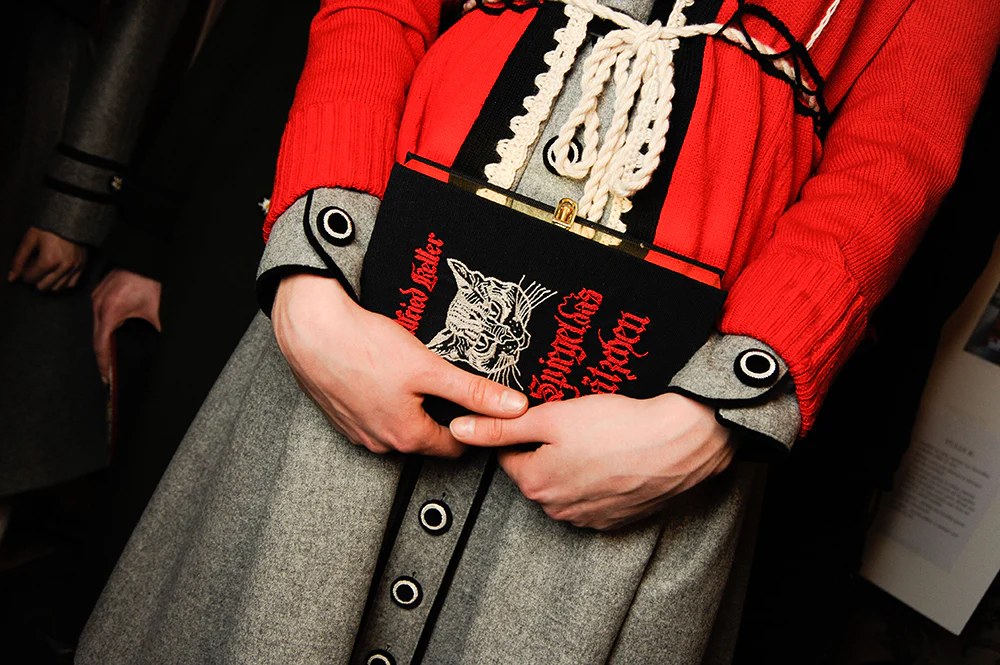 A woman holds a clutch shaped like a book.
