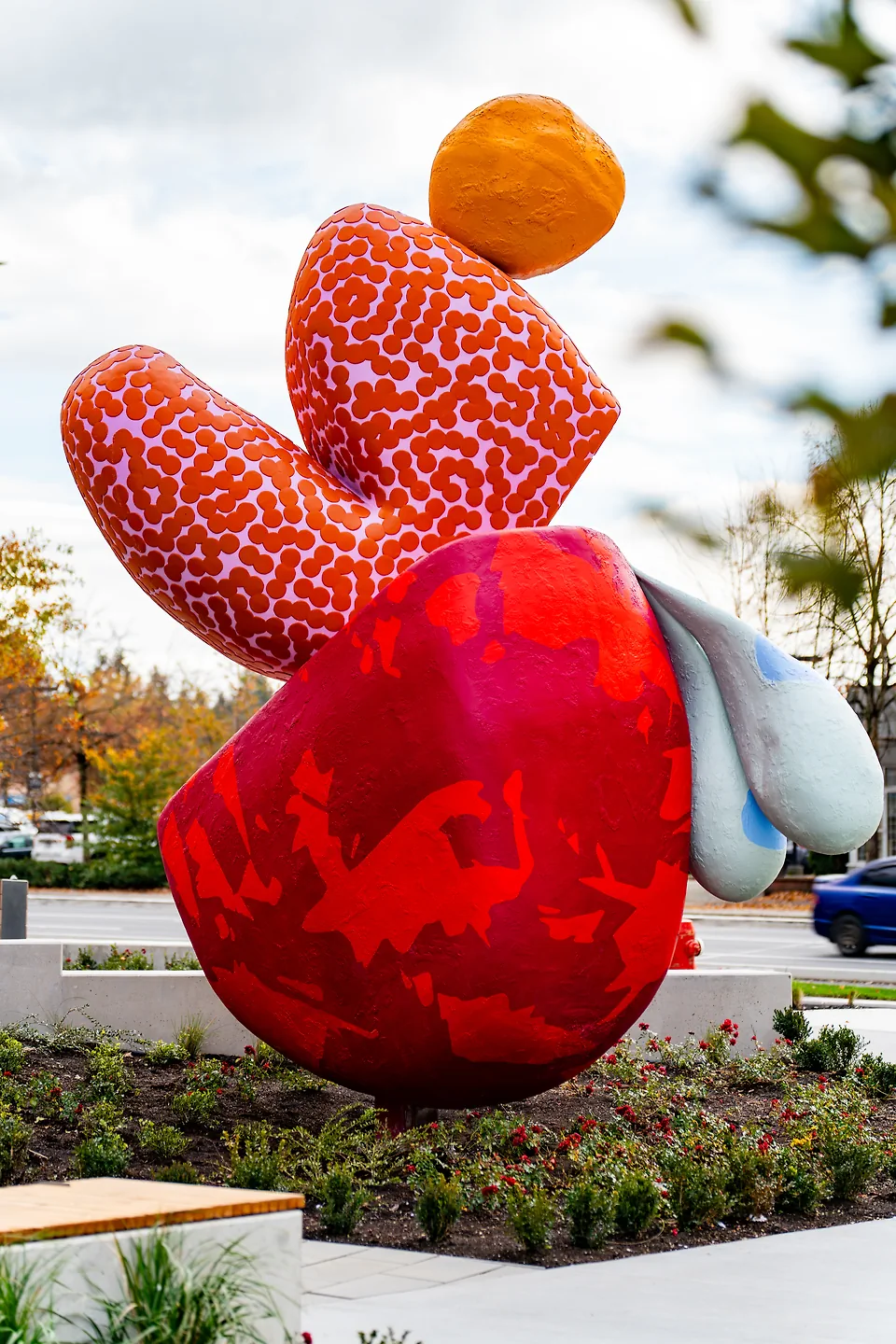 A red pink and orange statue outdoors.