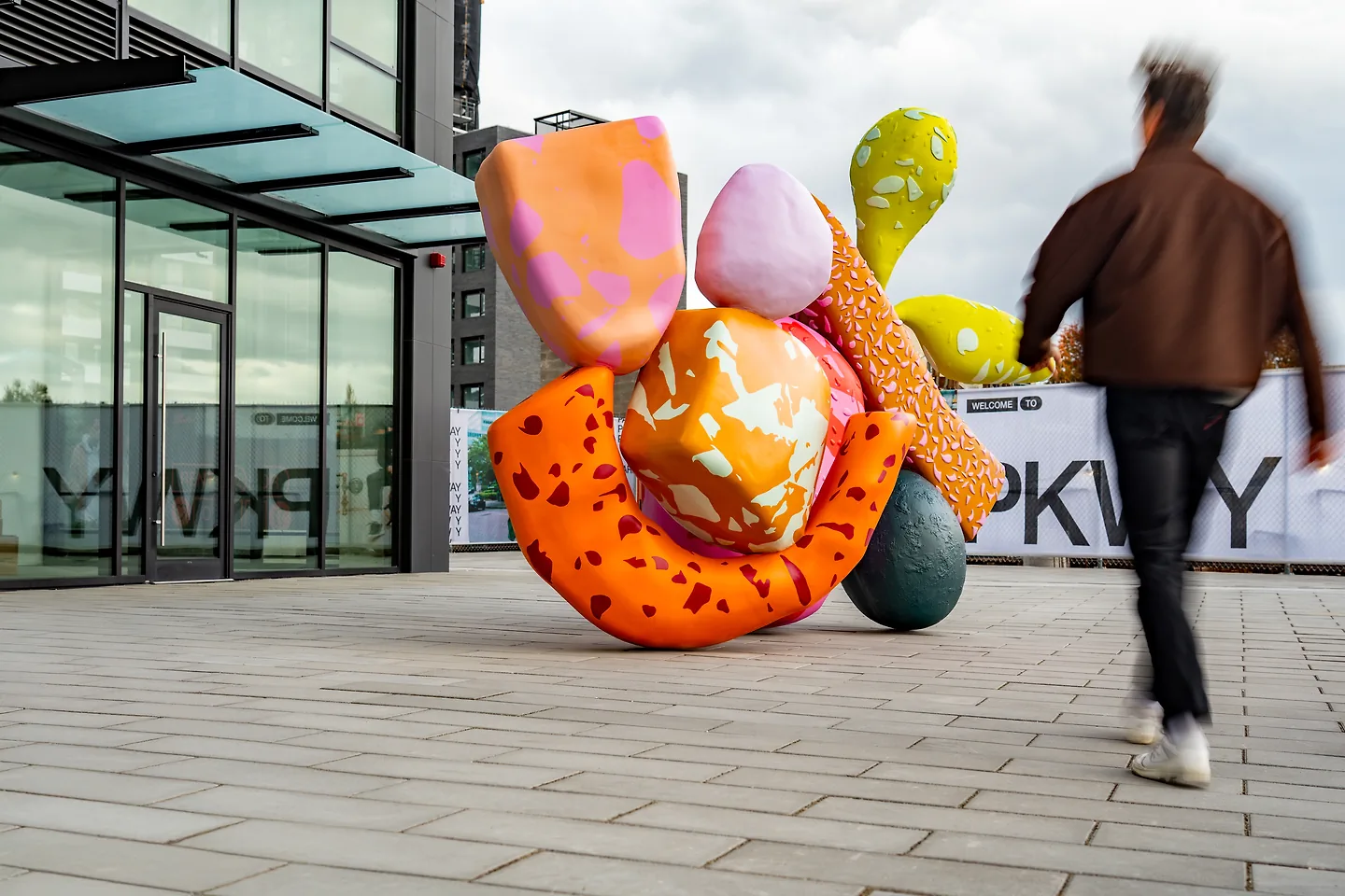 A person walks by a multi-coloured statue, part of Sanctuaries of Belonging.