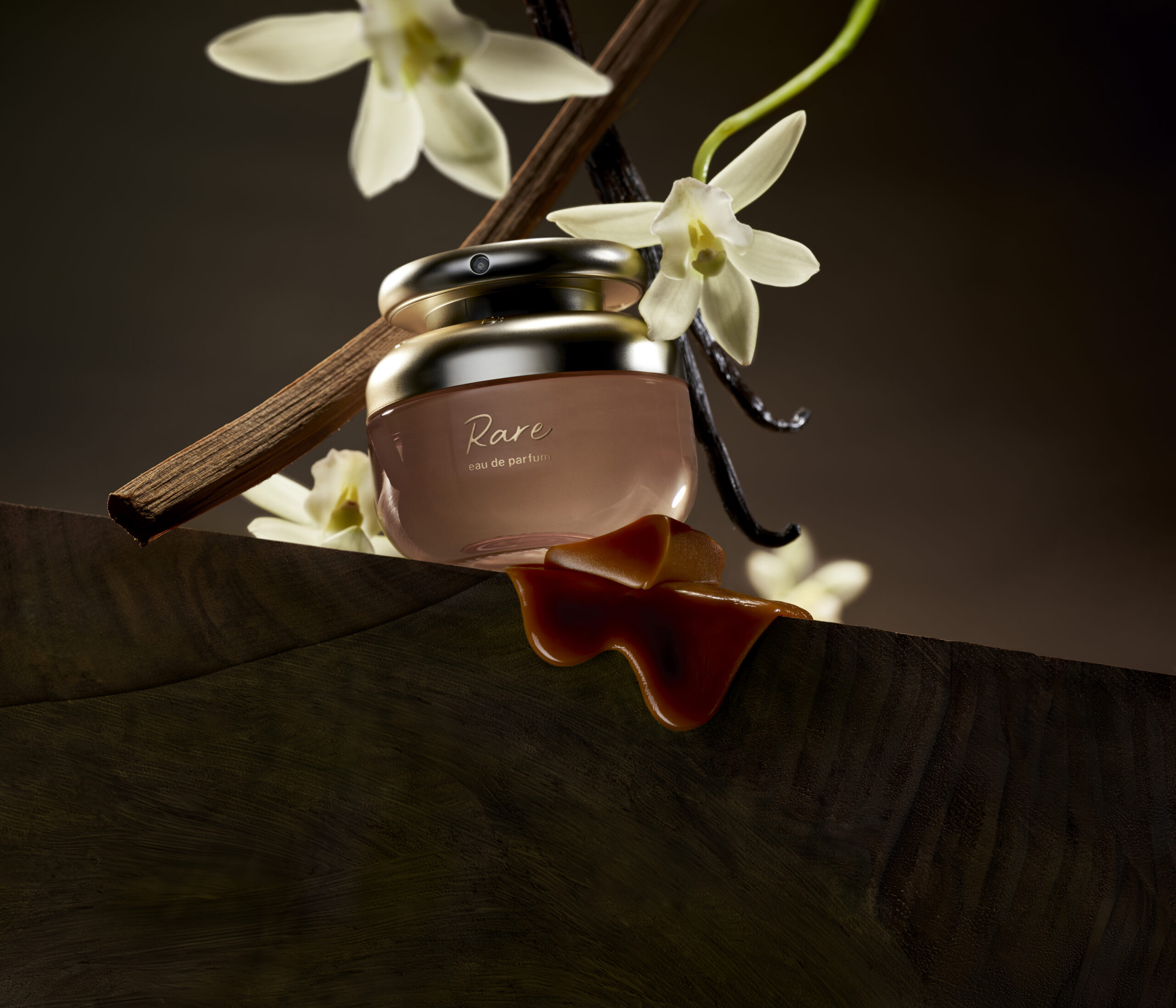 A perfume bottle surrounded by vanilla beans and blossoms.