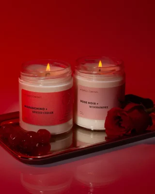 Two candles burning on a tray against a red background.